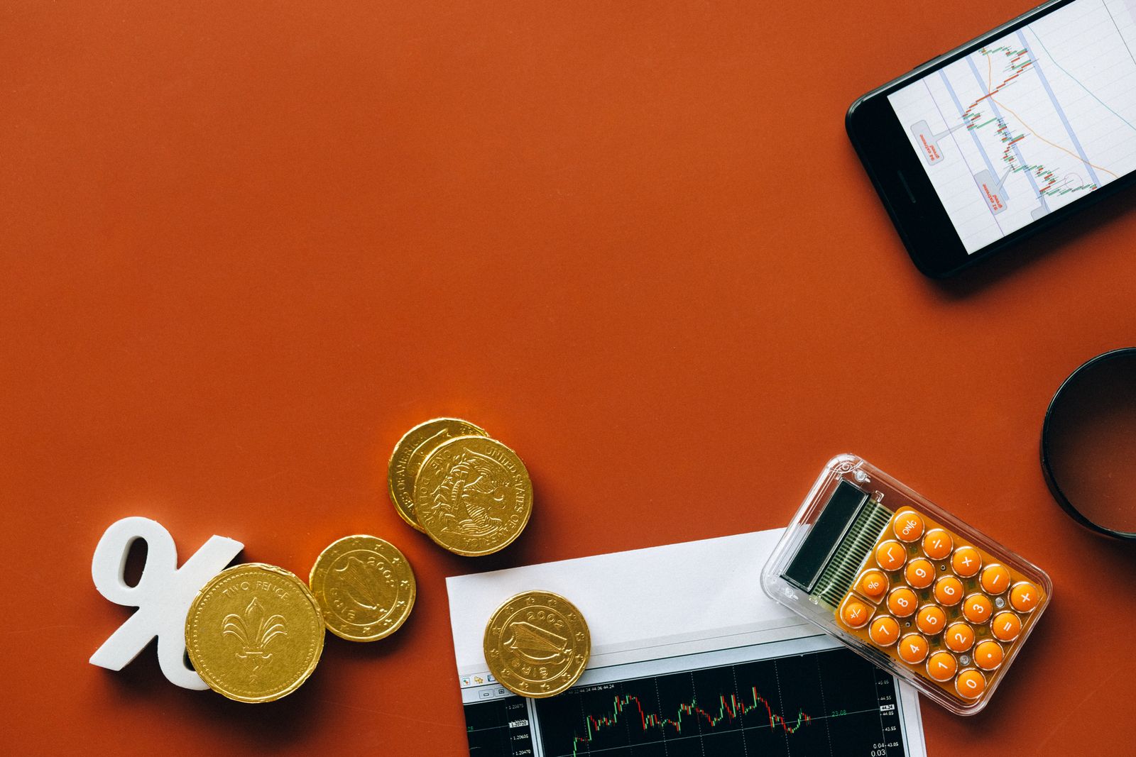 Pièces dorées, symbole pourcentage et calculatrice sur fond orange